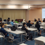 プレゼンする4名の学生と聞き入る20名ほどの聴講学生たち